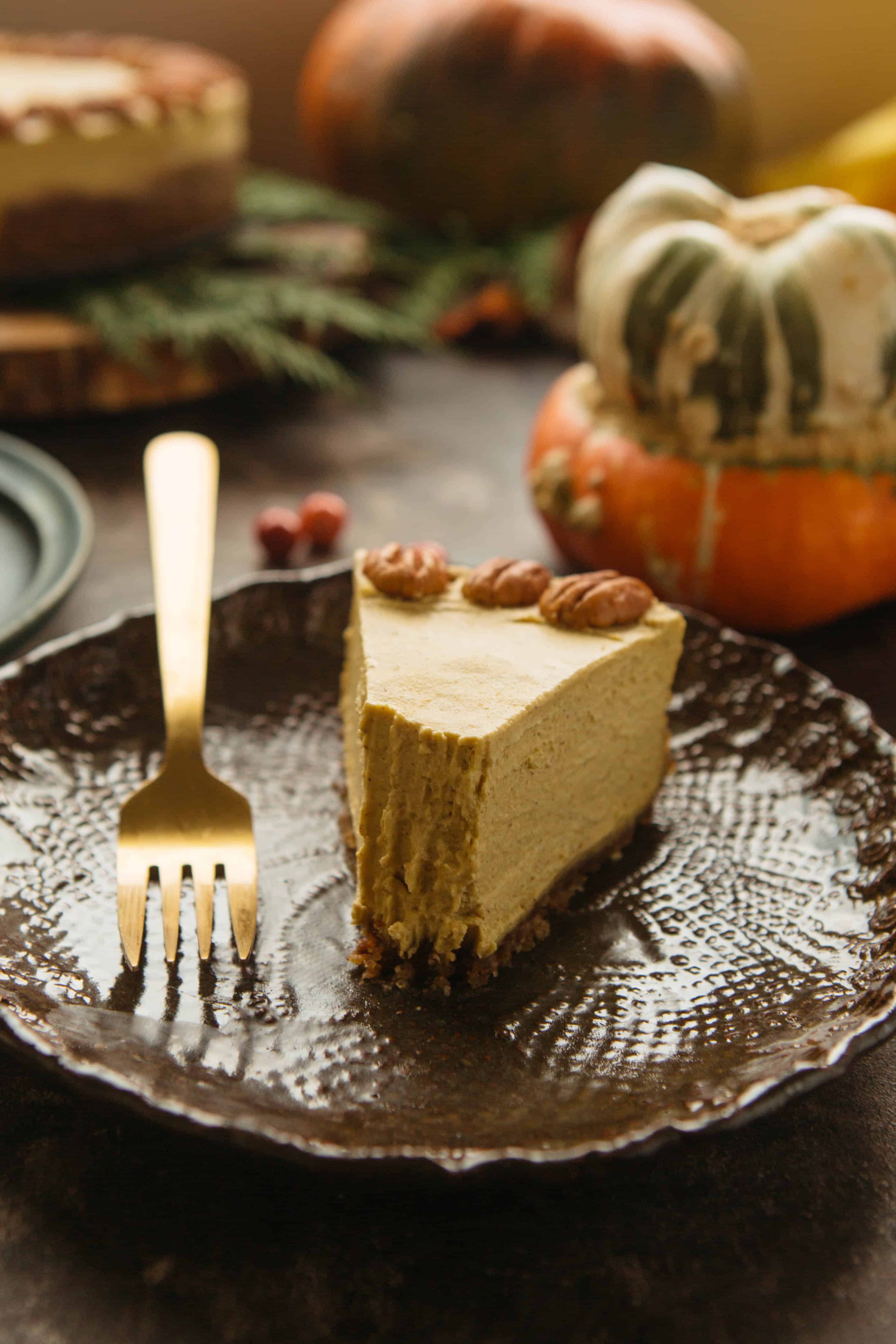 A close up of a dessert plate with a slice of vegan pumpkin cheesecake that has a bite removed.