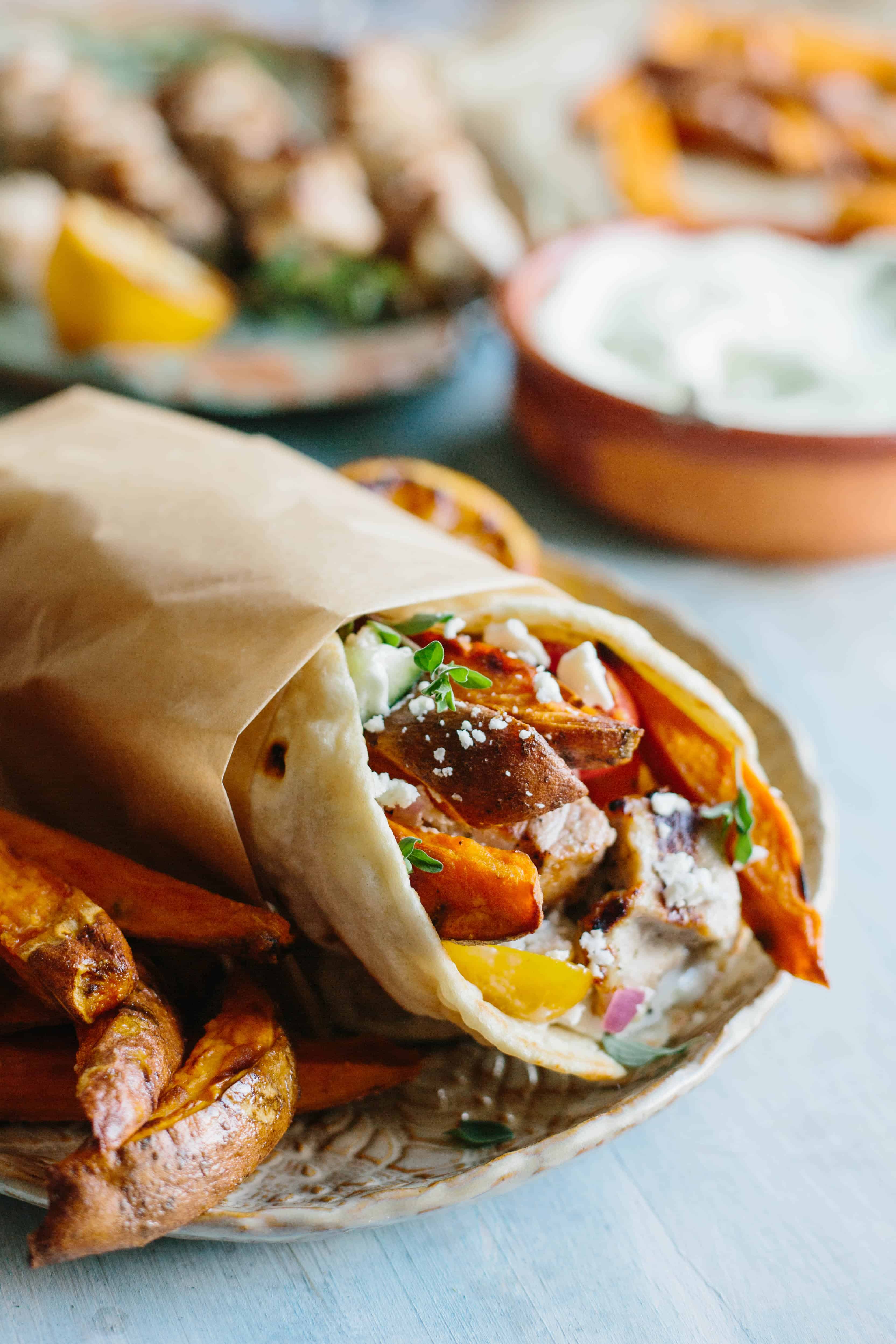 Close up of pork, sweet potatoes, and cucumber salad wrapped up in a pita.