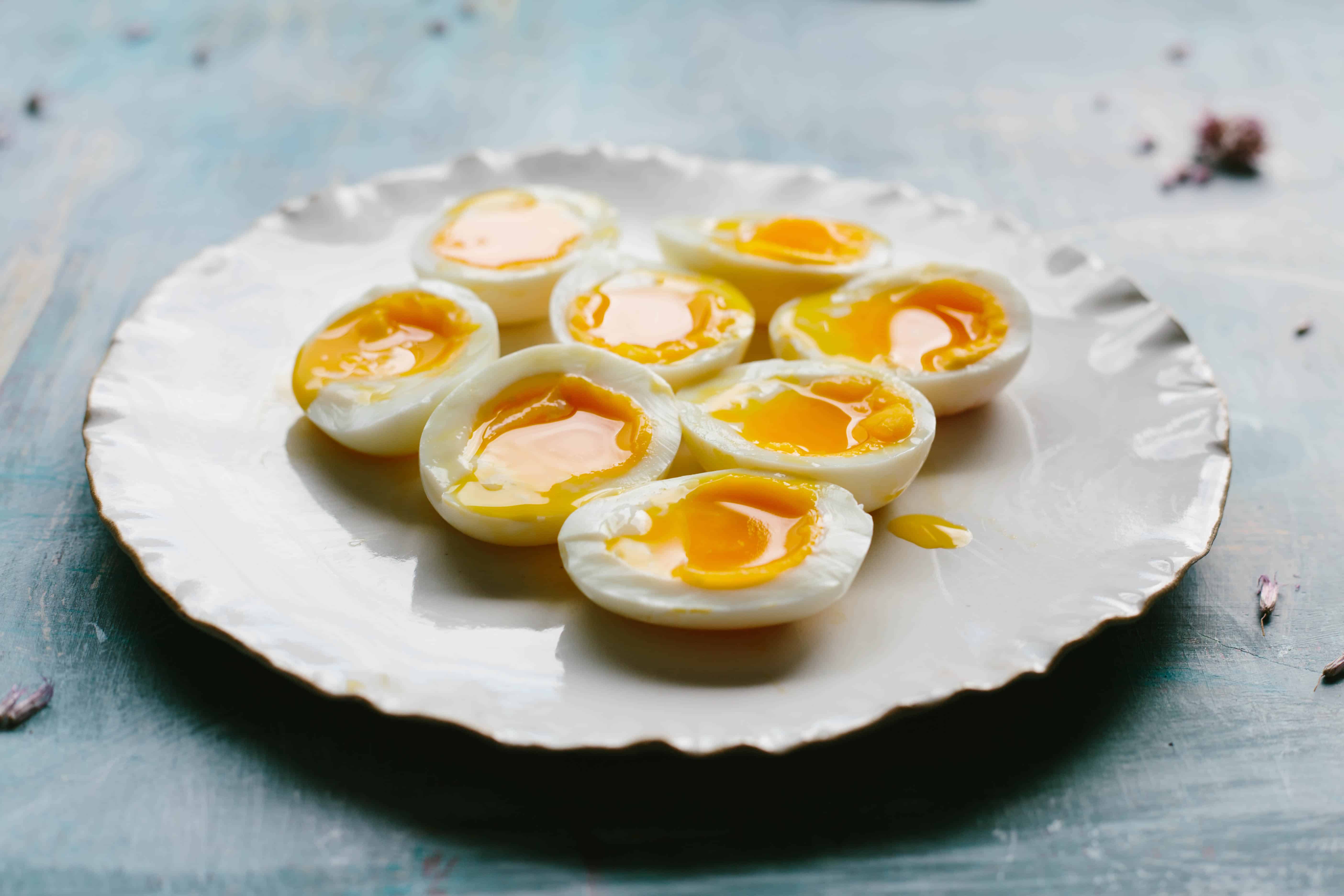 Eight soft boiled egg halves on a white plate.
