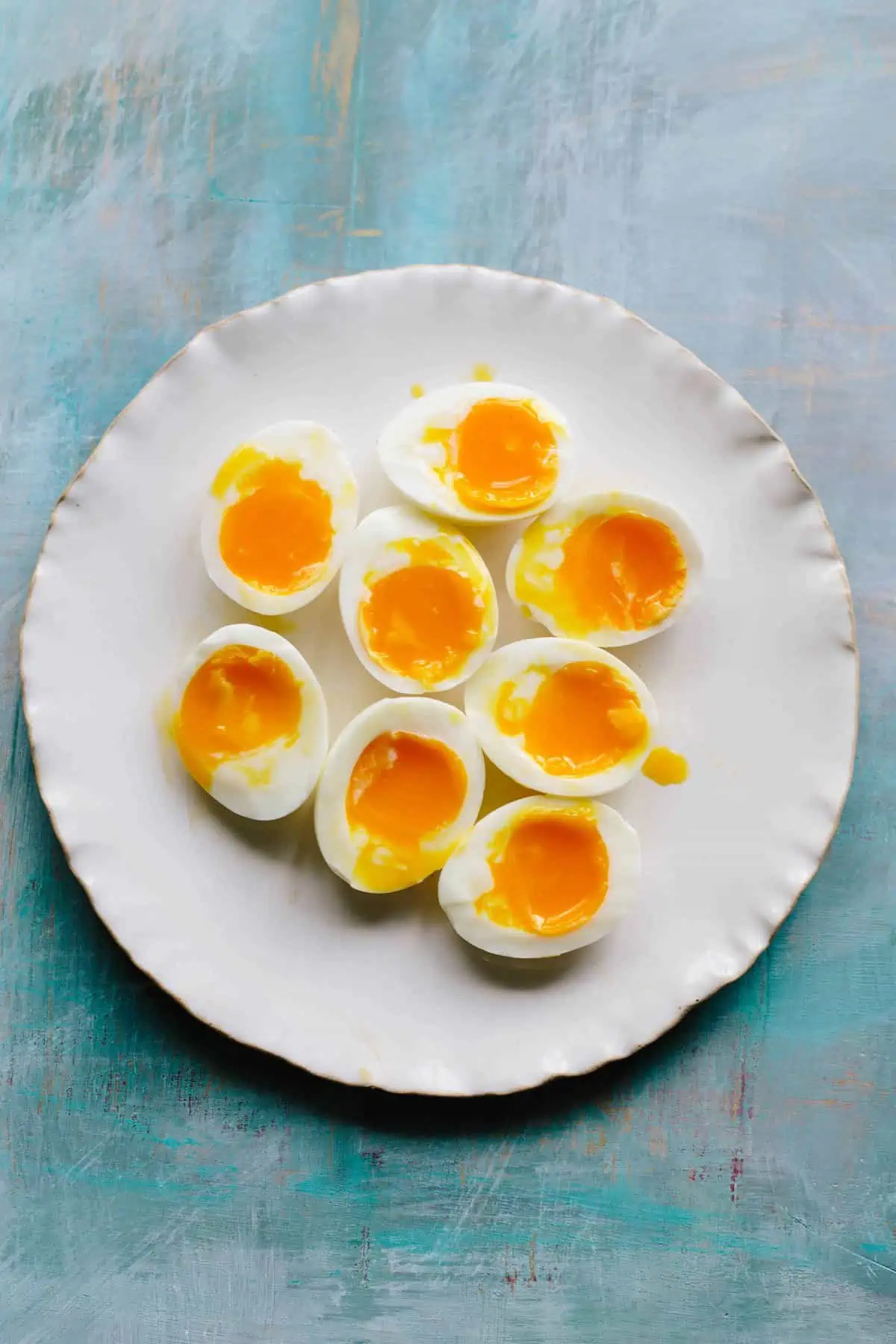 A white dinner plate with eight soft boiled egg halves.