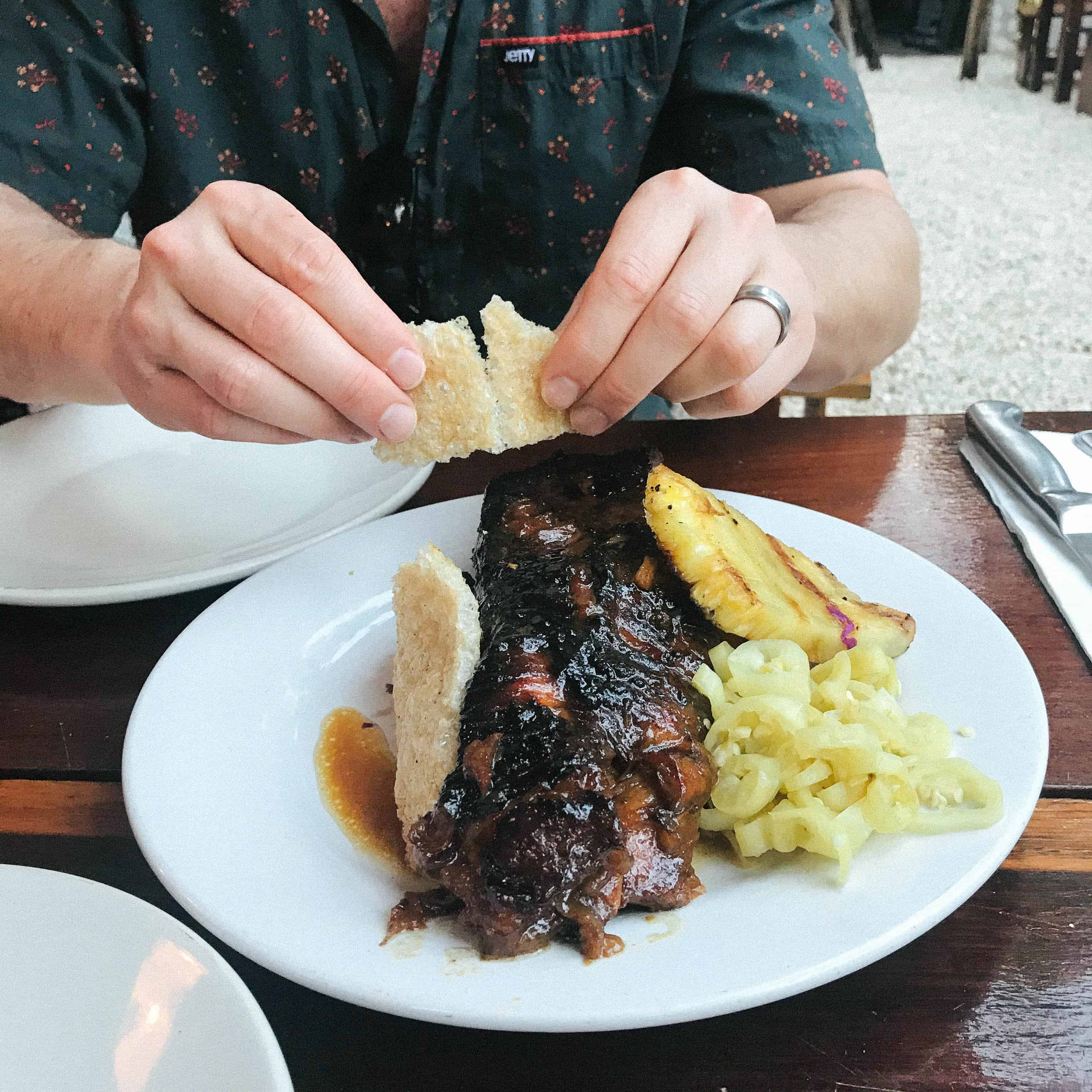 A man breaking crisp toast over braised shortribs.