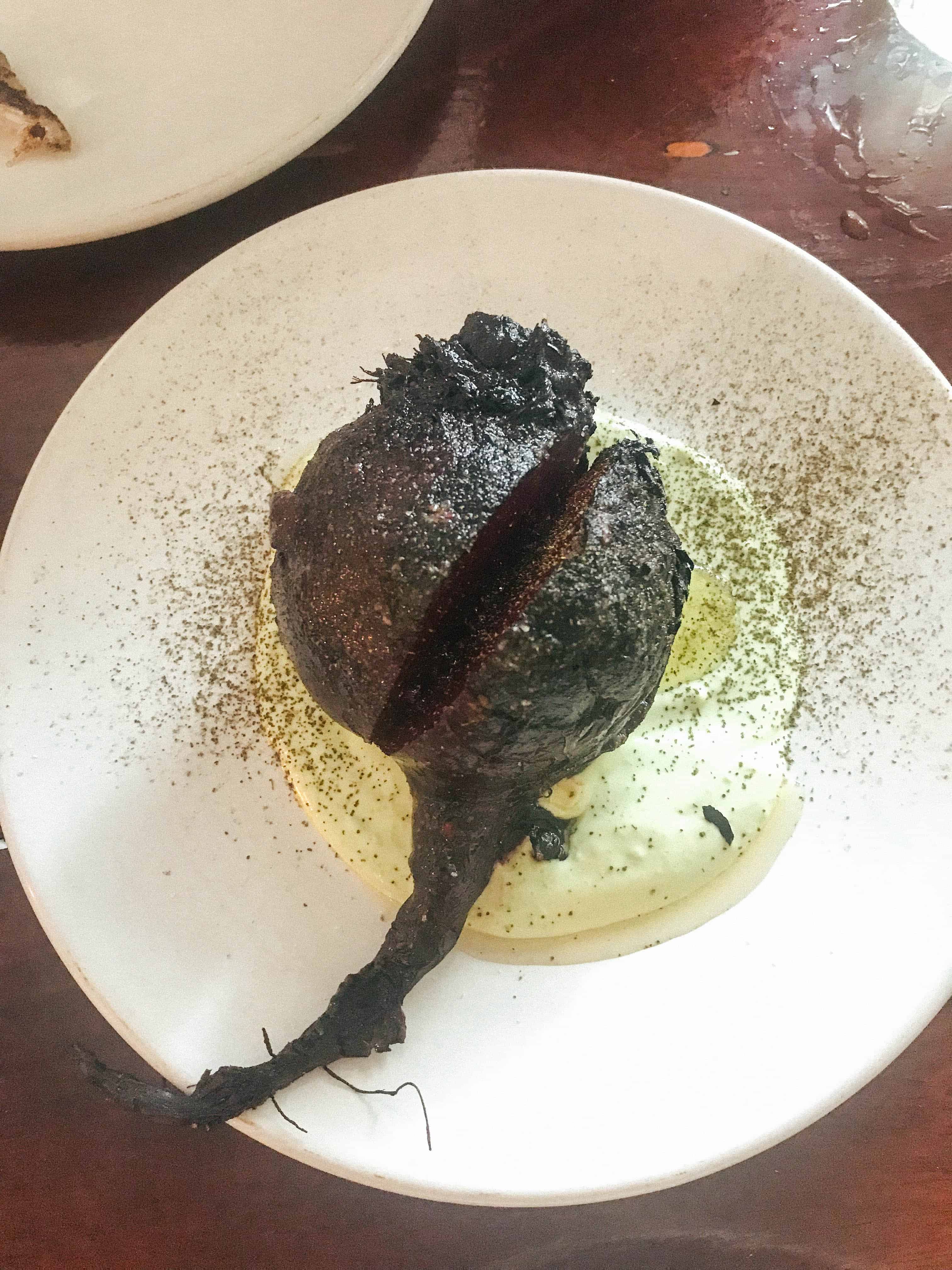 Single roasted beet on a white dinner plate.