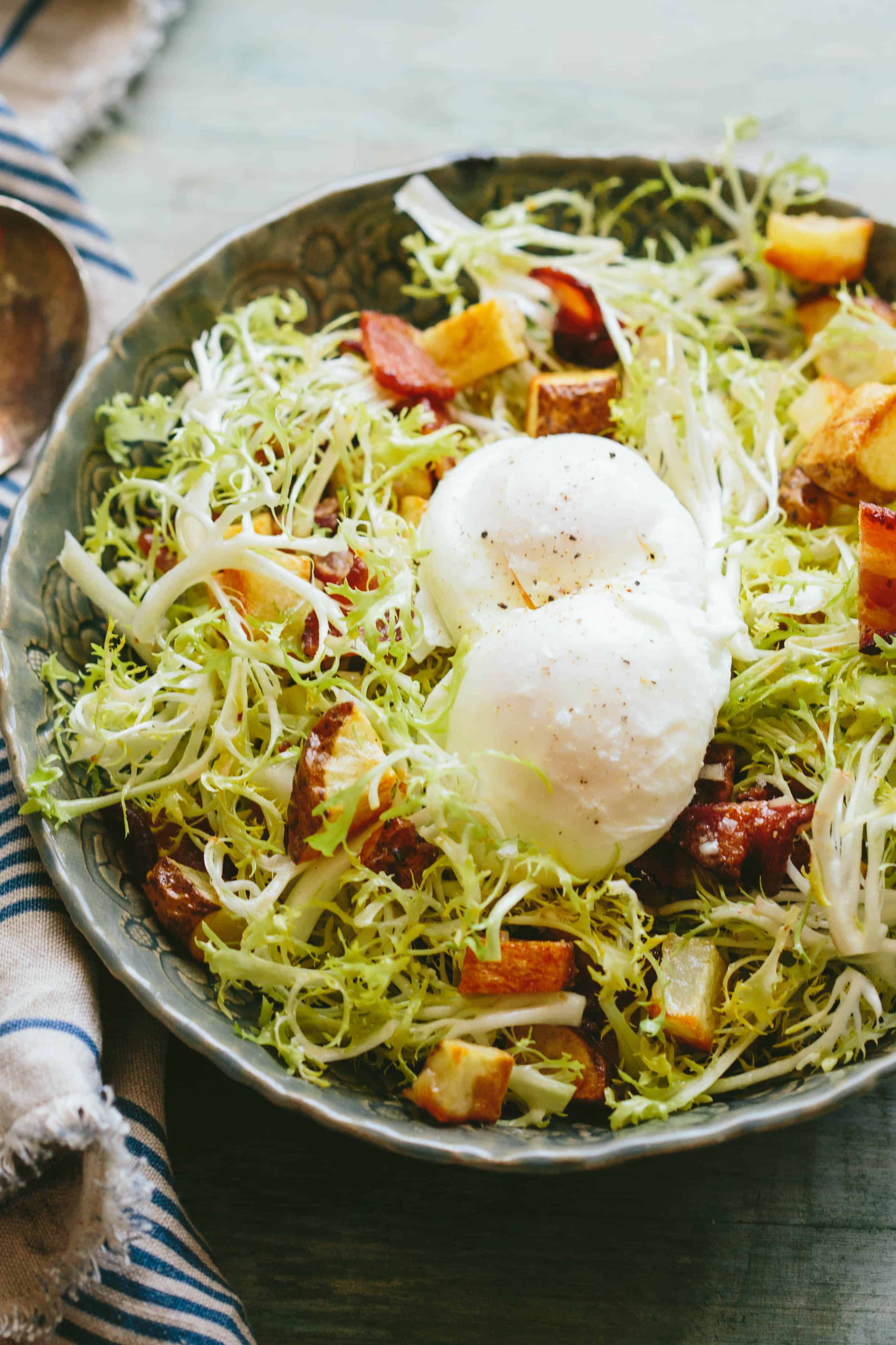 Top view of a serving bowl of lyonnaise salad with poached eggs on top.