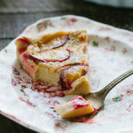 Triangle slice of plum clafoutis on a floral plate.