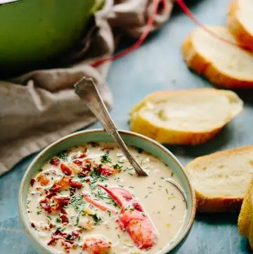 Vertical shot of  table with slices of toasted bread next to a bowl of lobster clam chowder.