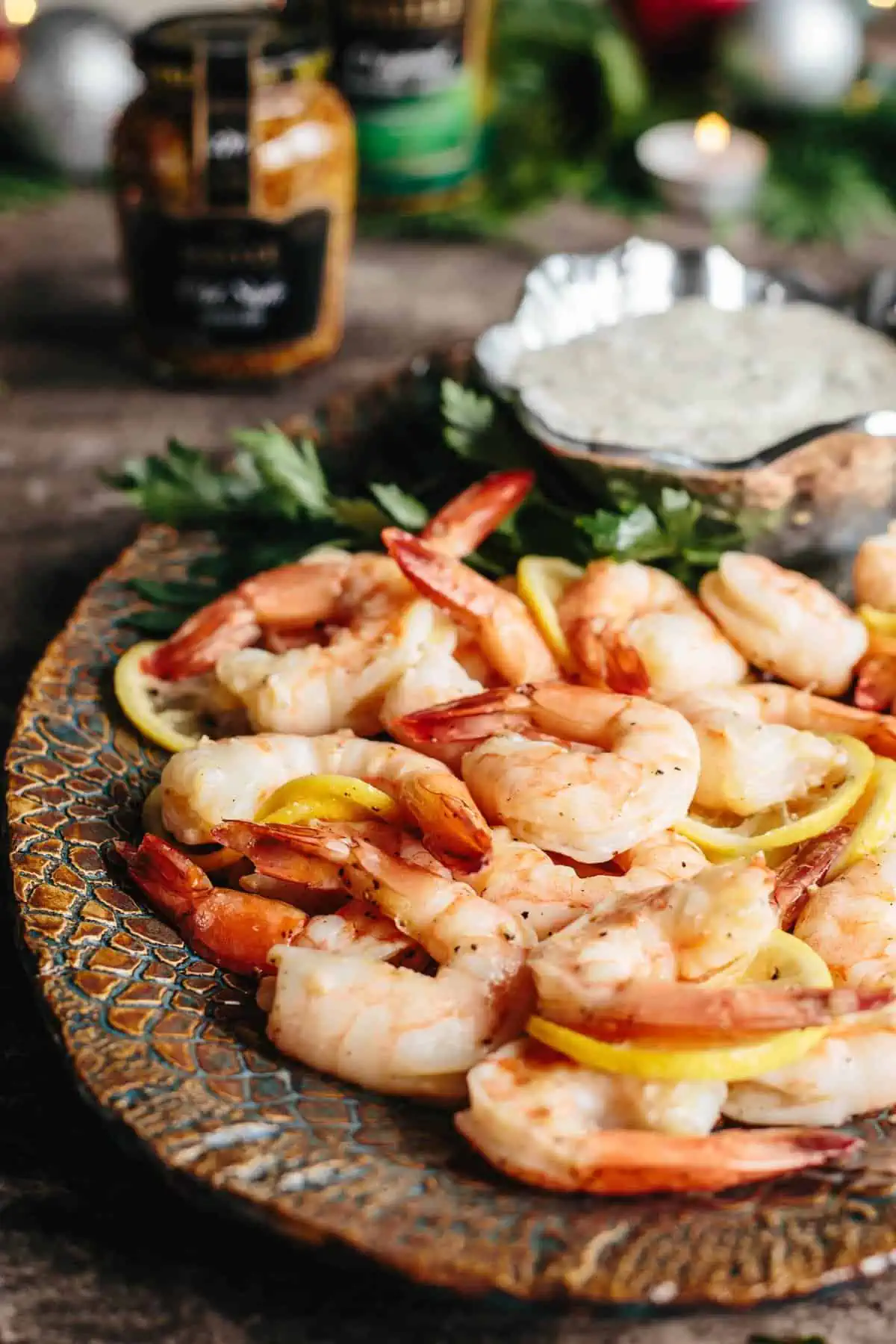 Close up of roasted shrimp mixed with thin slices of lemon on a platter.