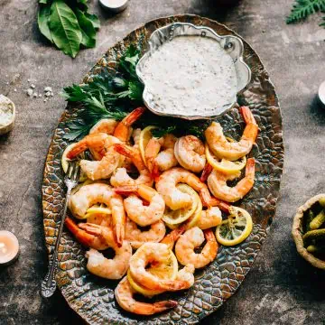 Roasted shrimp cocktail and a bowl of whole grain mustard sauce on a serving platter.