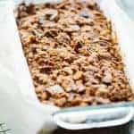 Closeup of the baked streusel topping on a loaf of Paleo banana bread in a glass loaf pan.