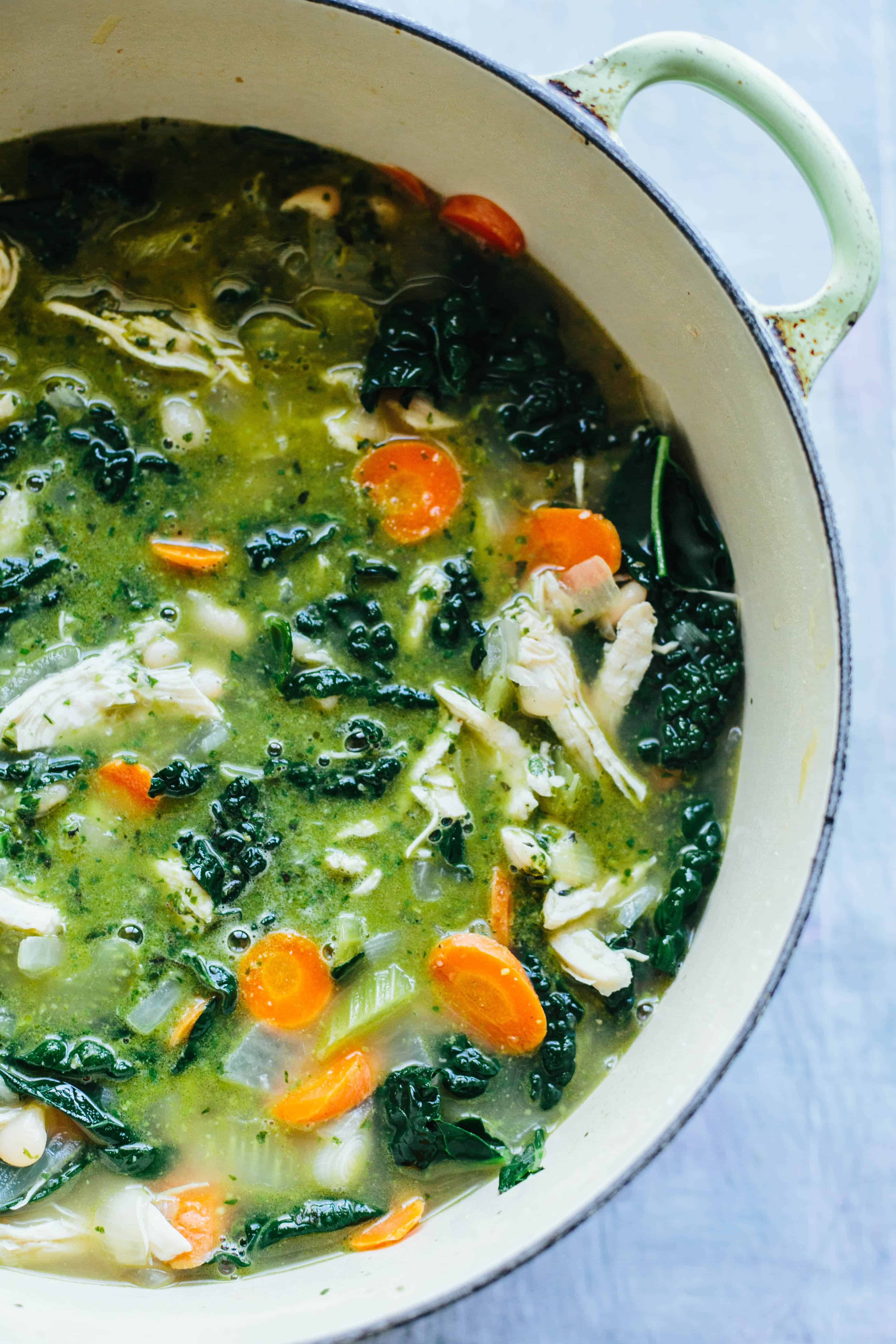 Top view of a cast iron Dutch oven filled with chicken white bean soup with kale.