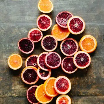 Colorful citrus cross sections spread out on a wooden tabletop.