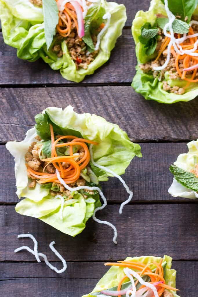 Closeup of a chicken lettuce wrap with pickled shredded carrots.