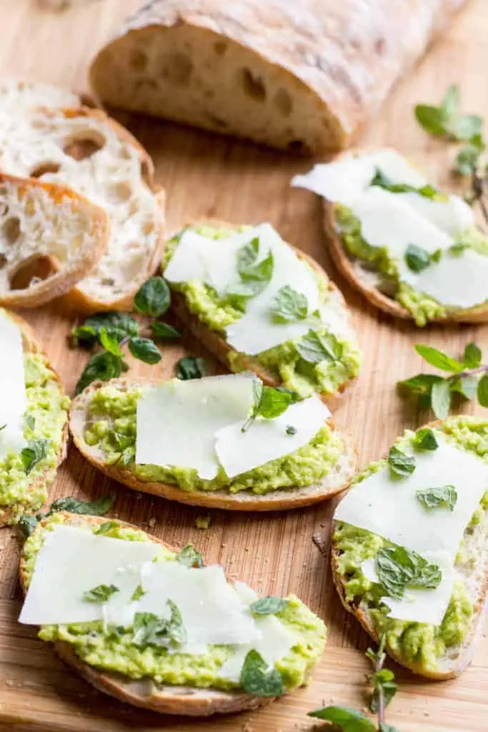 Close up of fava bean crostini topped with pecorino cheese.