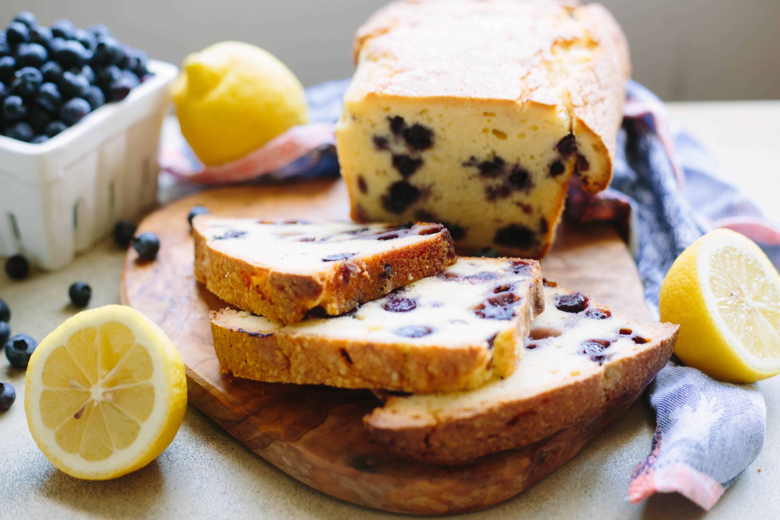 Lemon blueberry pound cake slices on a wood cutting board.