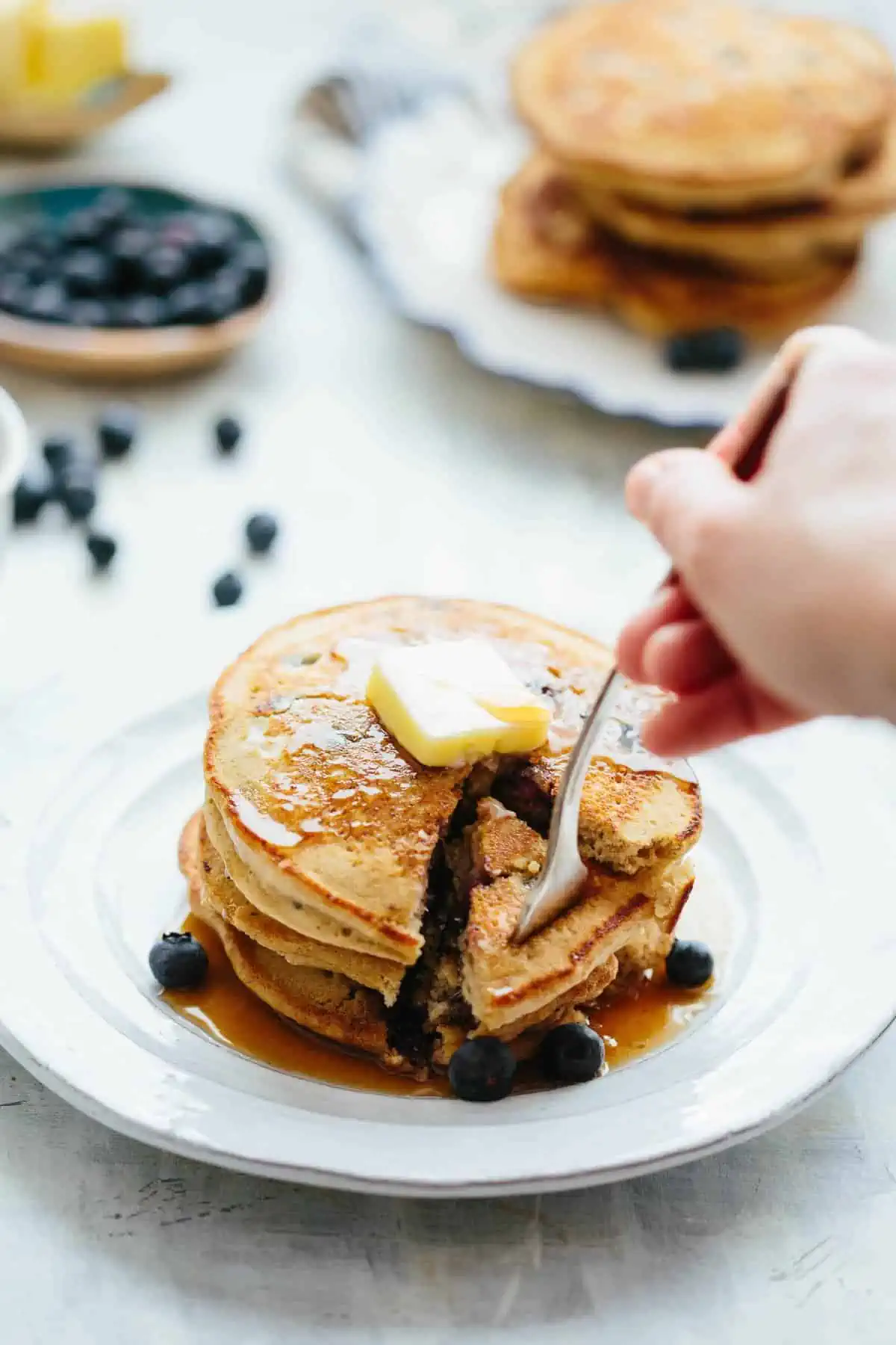 A fork digging into a stack of blueberry oatmeal pancakes.