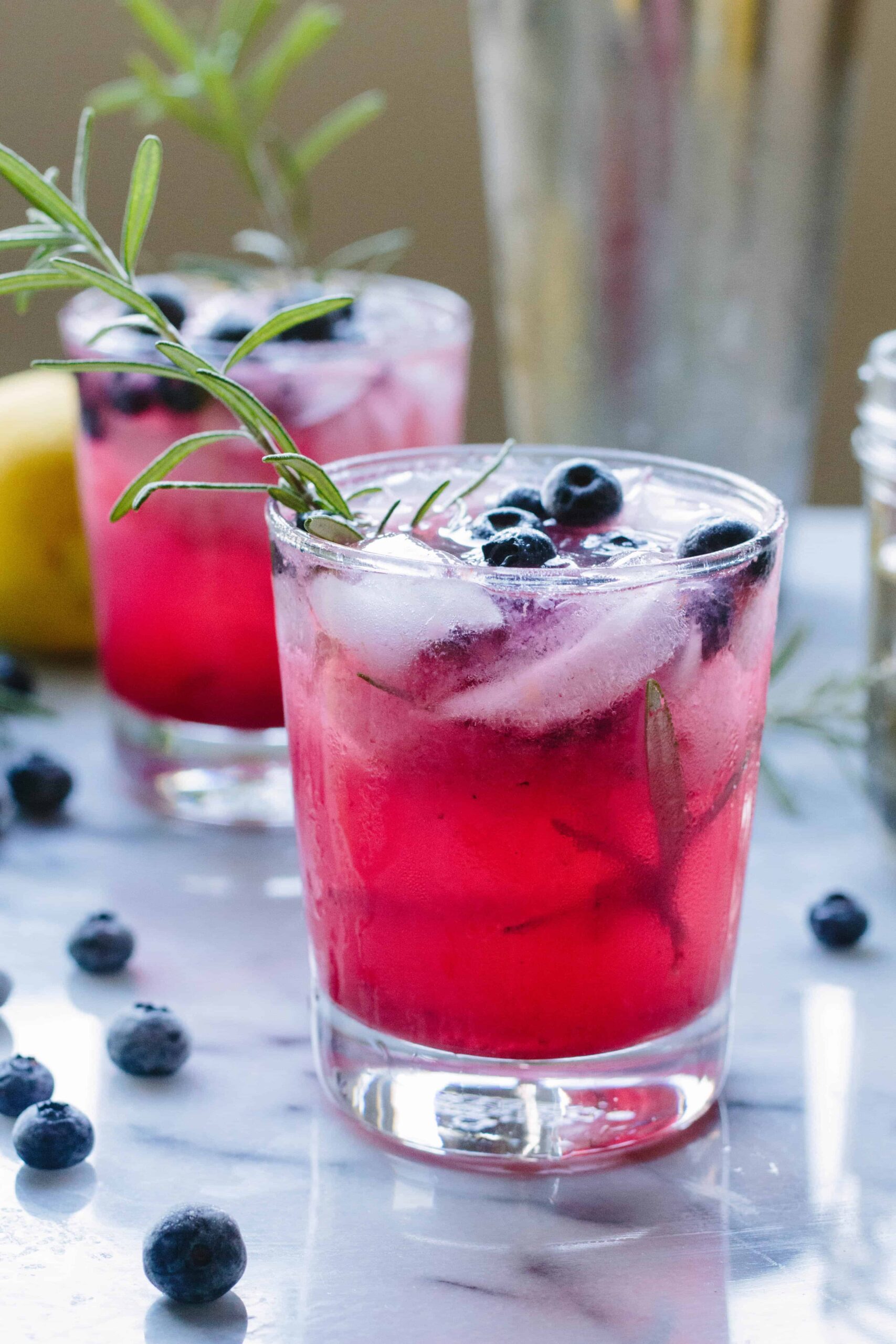Side view of two glasses of blueberry vodka spritzers.