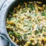 Cast iron skillet filled with broccoli rabe, sausage, and chickpea pasta.