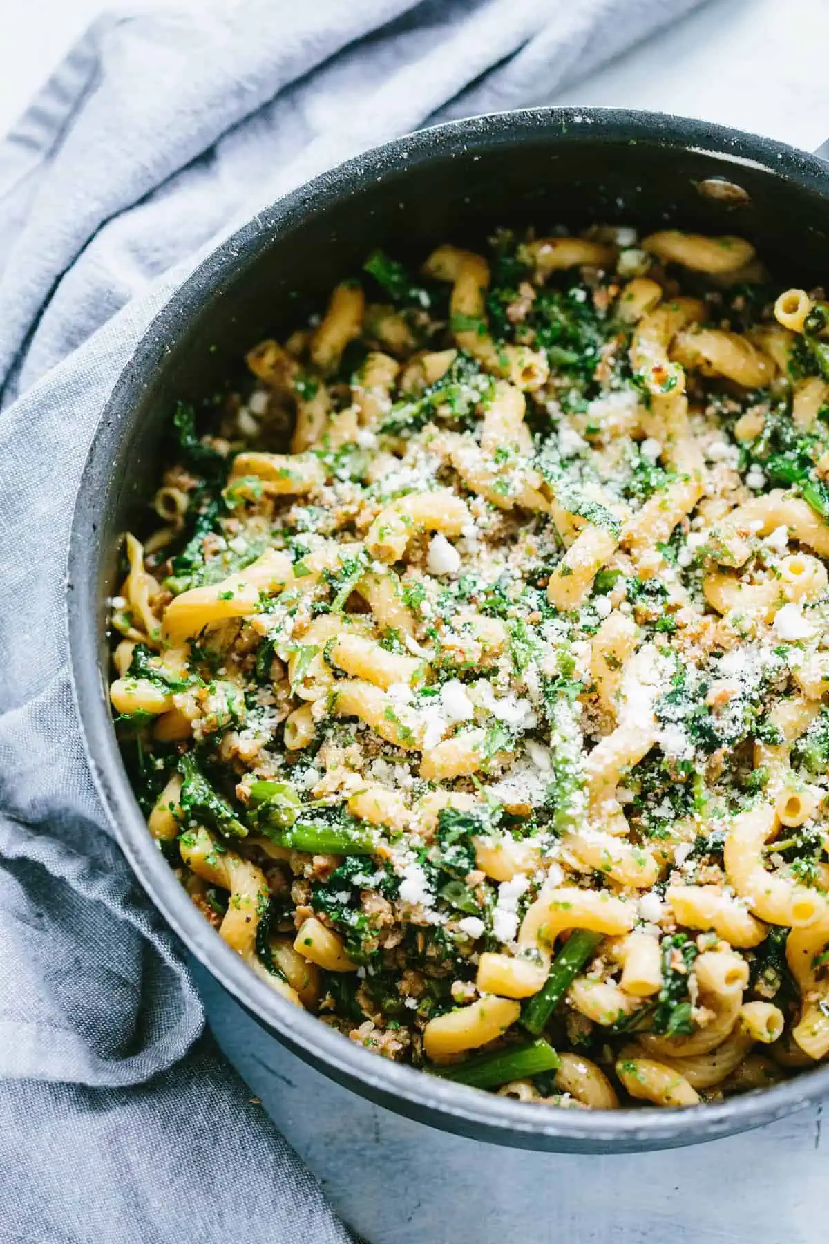 Cast iron skillet filled with broccoli rabe, sausage, and chickpea pasta.