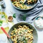 Bowl and skillet both filled with chickpea pasta with sausage and broccoli rabe.