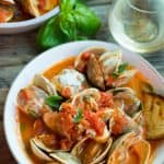Baked clams in tomato sauce in a white serving bowl.