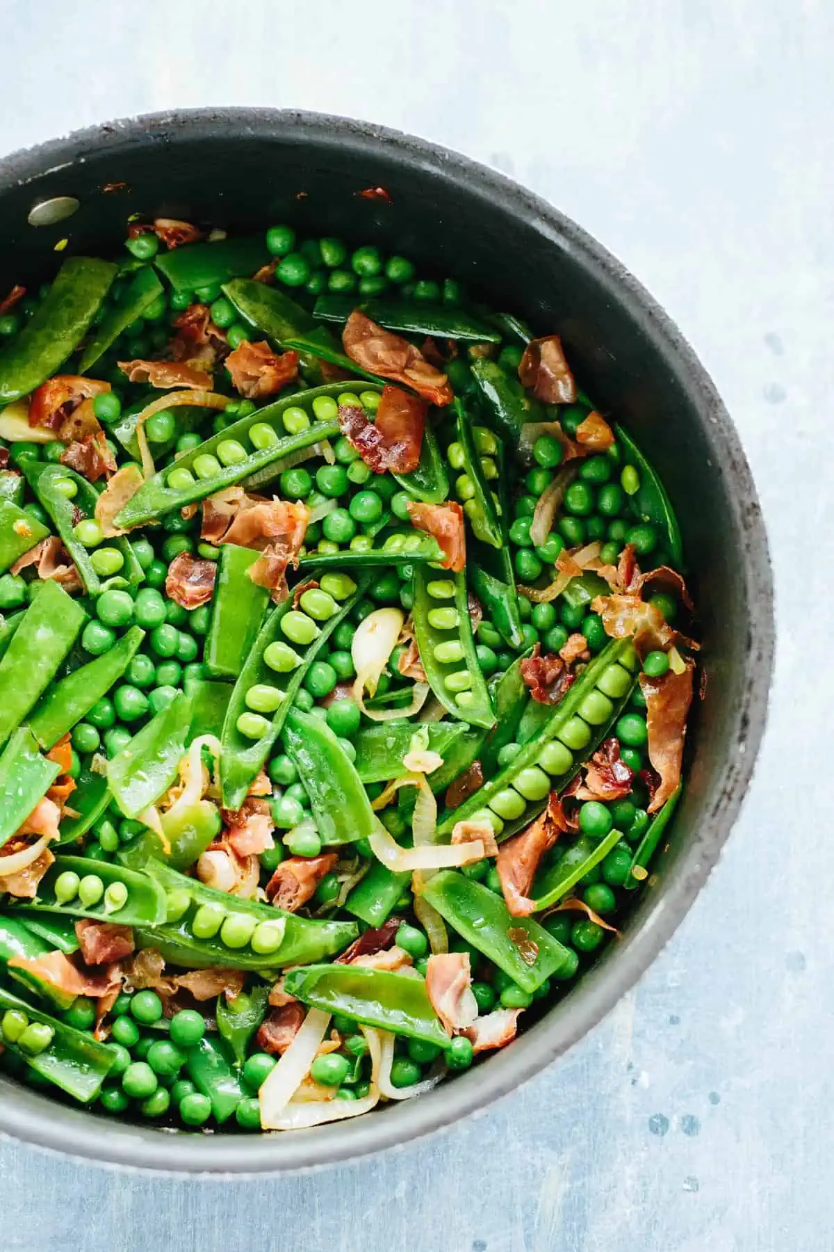 Beautiful bowl of spring pea pods mixed with crispy prosciutto.