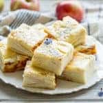 Side view of sliced apple custard bars stacked on a plate.