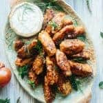 Fried Greek tomato fritters stacked on an oval platter with a bowl of tzatziki.