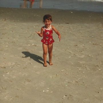 A little girl that is standing in the sand on a beach
