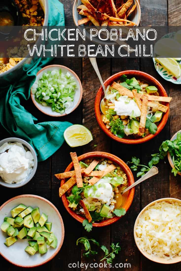 Vertical image of a table filled with bowls of poblano white bean chicken chili and all the toppings.