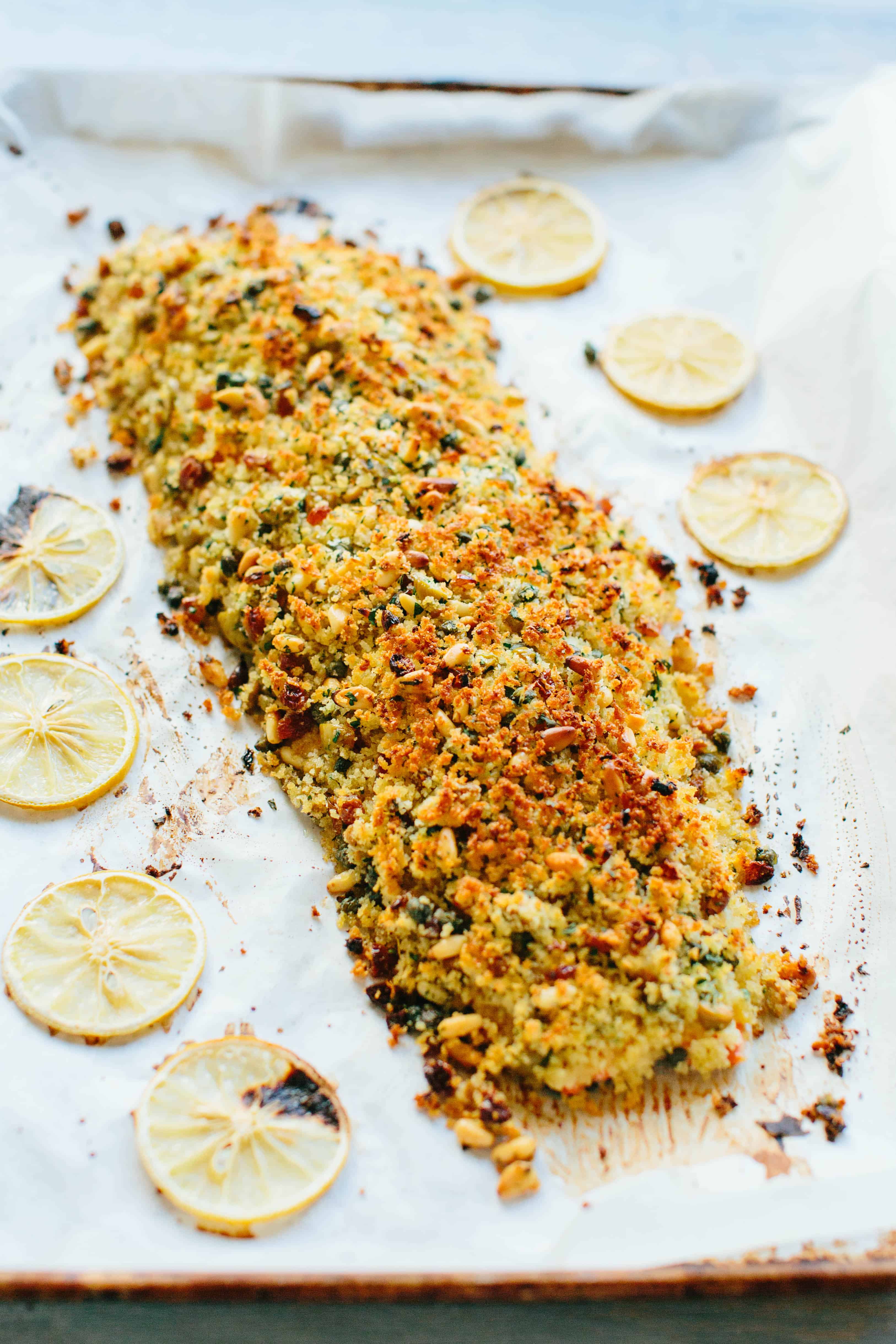 A whole fillet of roasted salmon with breadcrumbs and lemon on a sheet pan