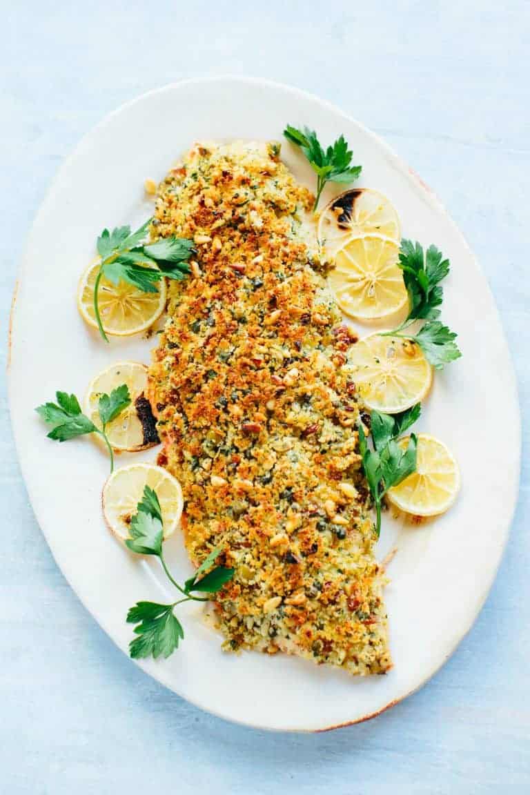 Alaskan baked salmon with a breadcrumb crust served on a platter with lemon slices. 