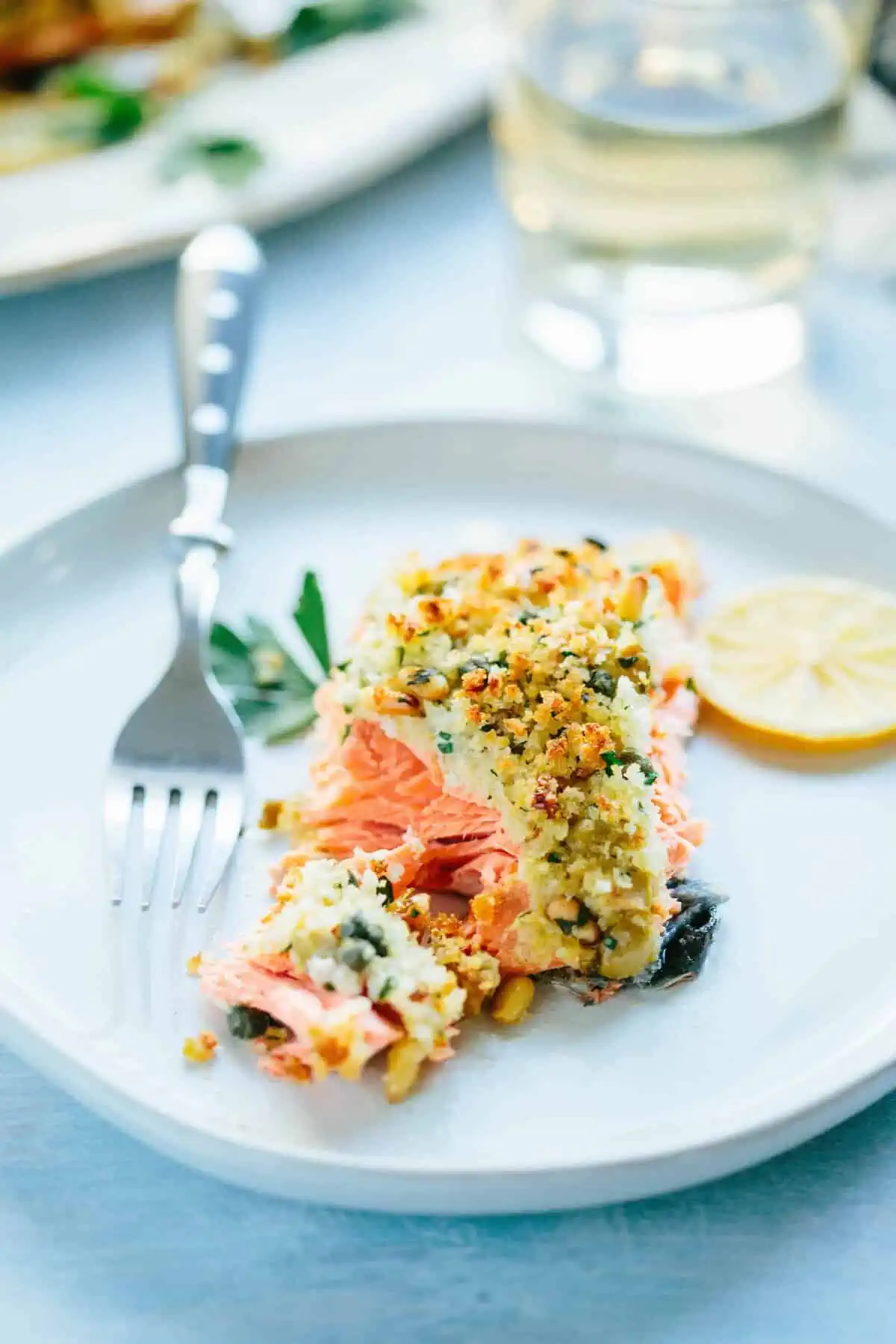A close up of a piece of Sicilian baked salmon being flaked apart with a fork