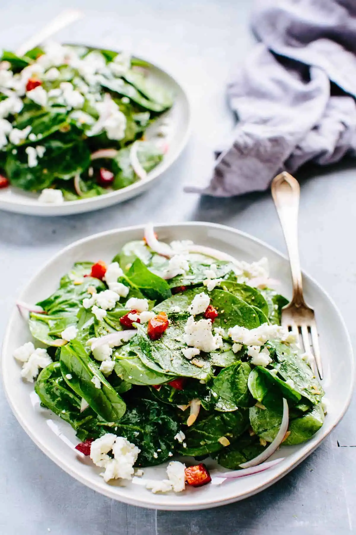 A plate of spinach salad with goat cheese
