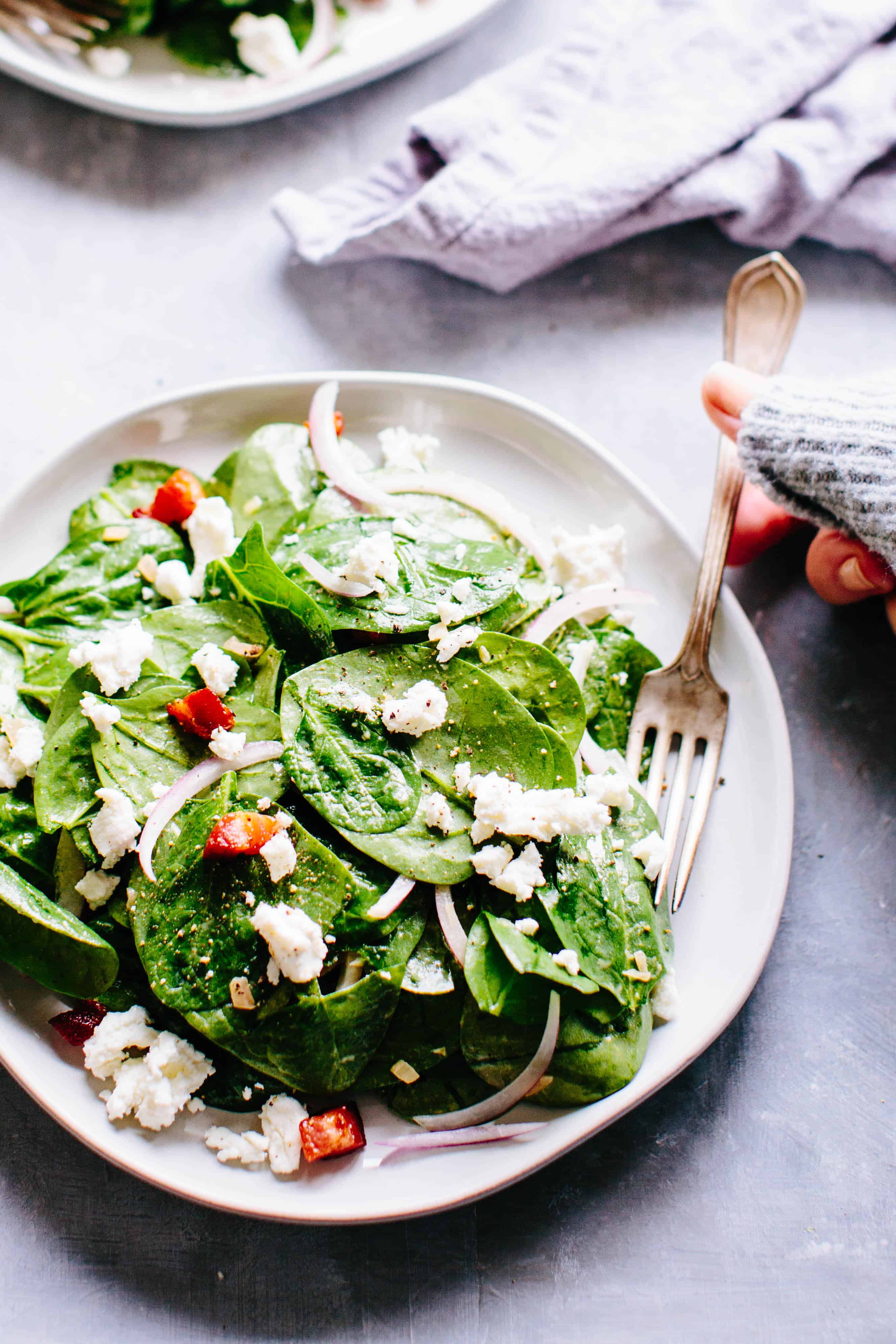 A plate of spinach salad with a fork