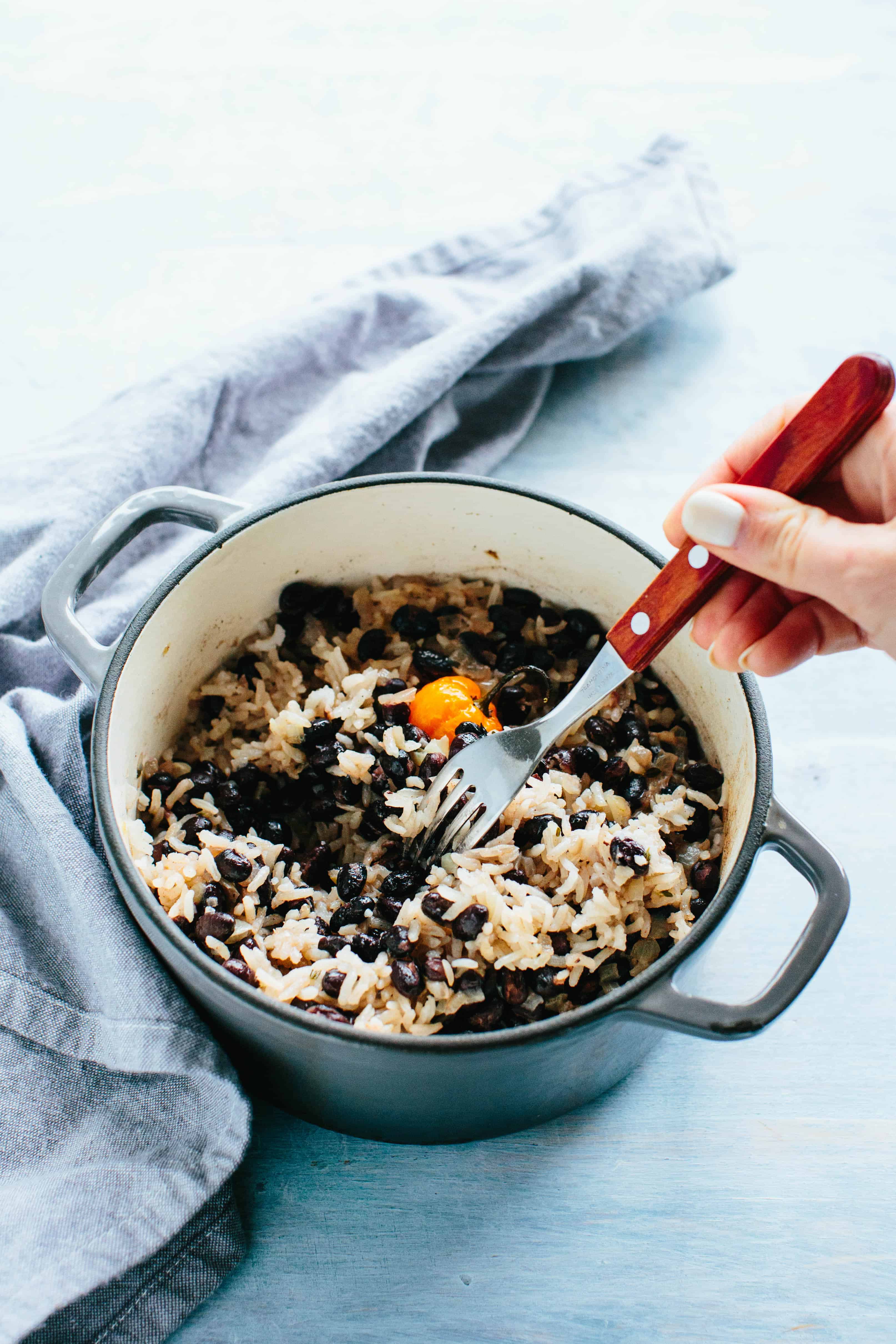 A pot of black beans and rice with a fork