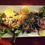 Top view of a whole grilled snapper on a white serving platter.