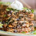 Side view of a slice of taco cake topped with a dollop of sour cream.