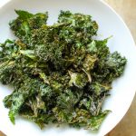 Top view of kale chips in a shallow white bowl.