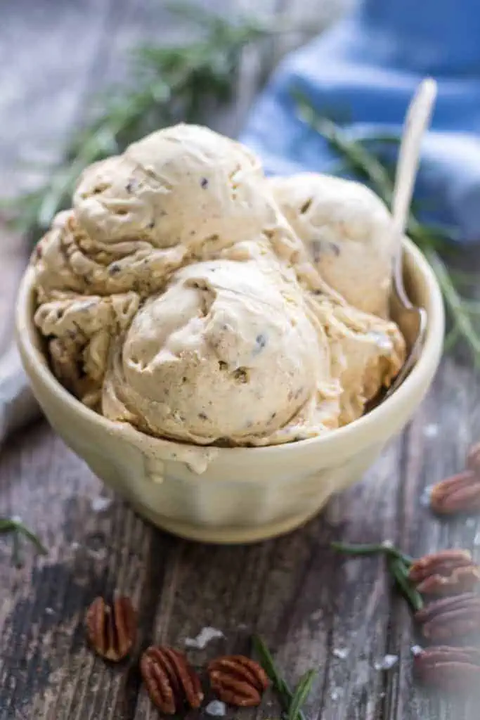 Close up of a bowl filled with scoops of brown butter pecan ice cream.