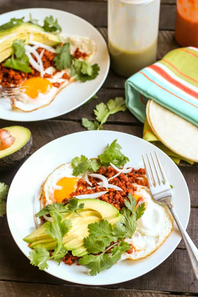 Top view of two dinner plates with sliced avocado and chorizo con huevos.