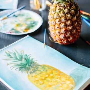 A painting of a pineapple and a real pineapple sitting on a table