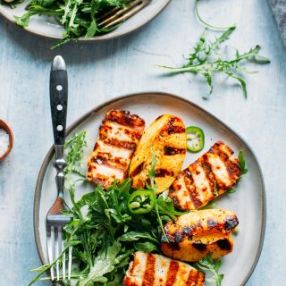 overhead shot of grilled halloumi and peaches with arugula, jalapeños and honey lemon vinaigrette