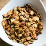 Top view of a small white bowl of jerk roasted pumpkin seeds.
