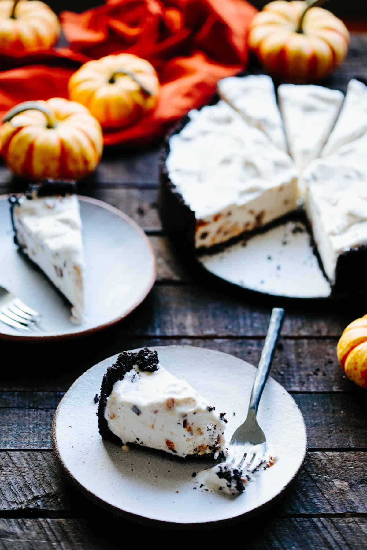 slices of ice cream pie on white plates with pumpkins and dark background