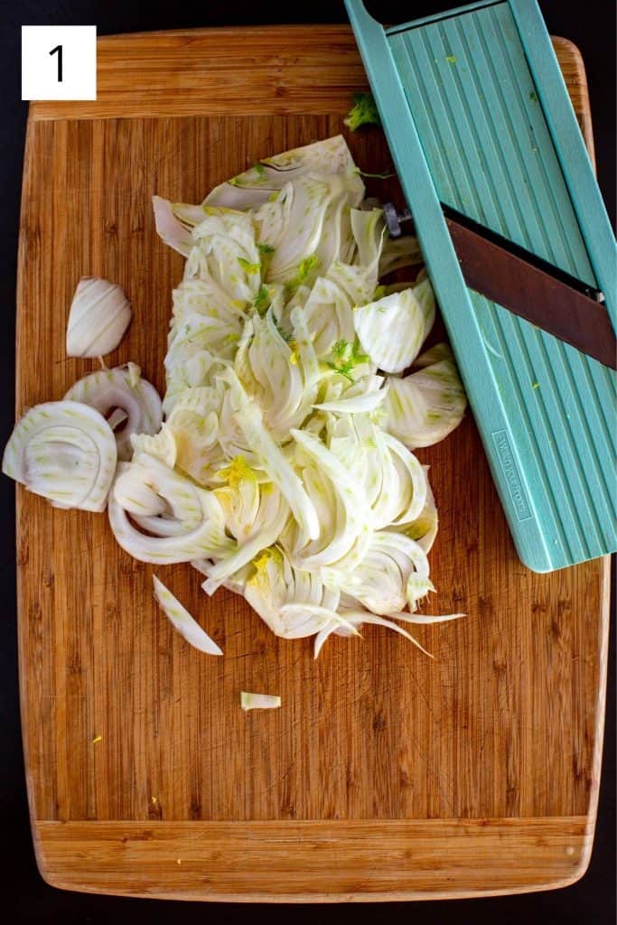 fennel being sliced on a mandolin on a wood cutting board