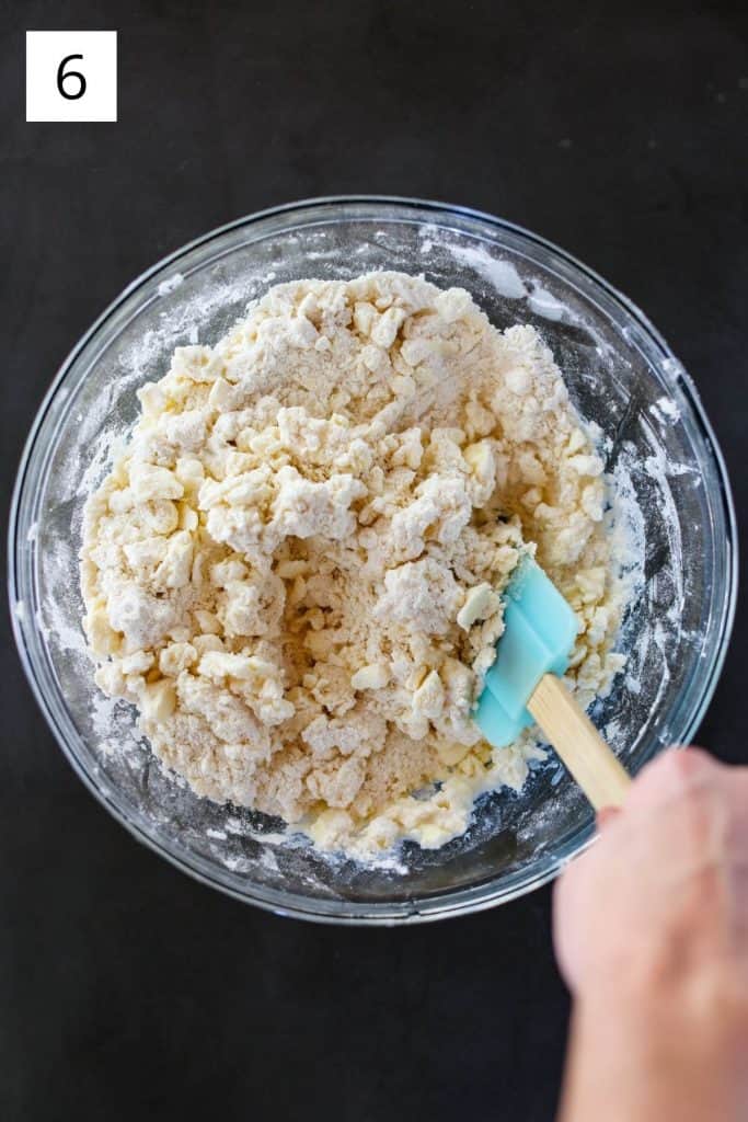 mixing pie dough in a bowl with rubber spatula