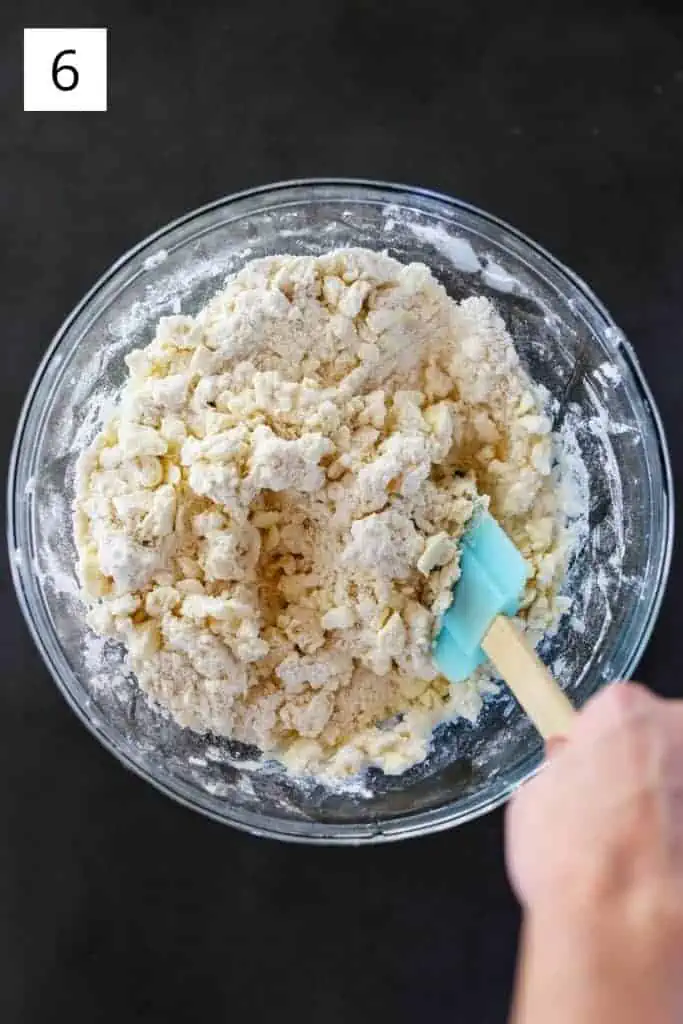 mixing pie dough in a bowl with rubber spatula