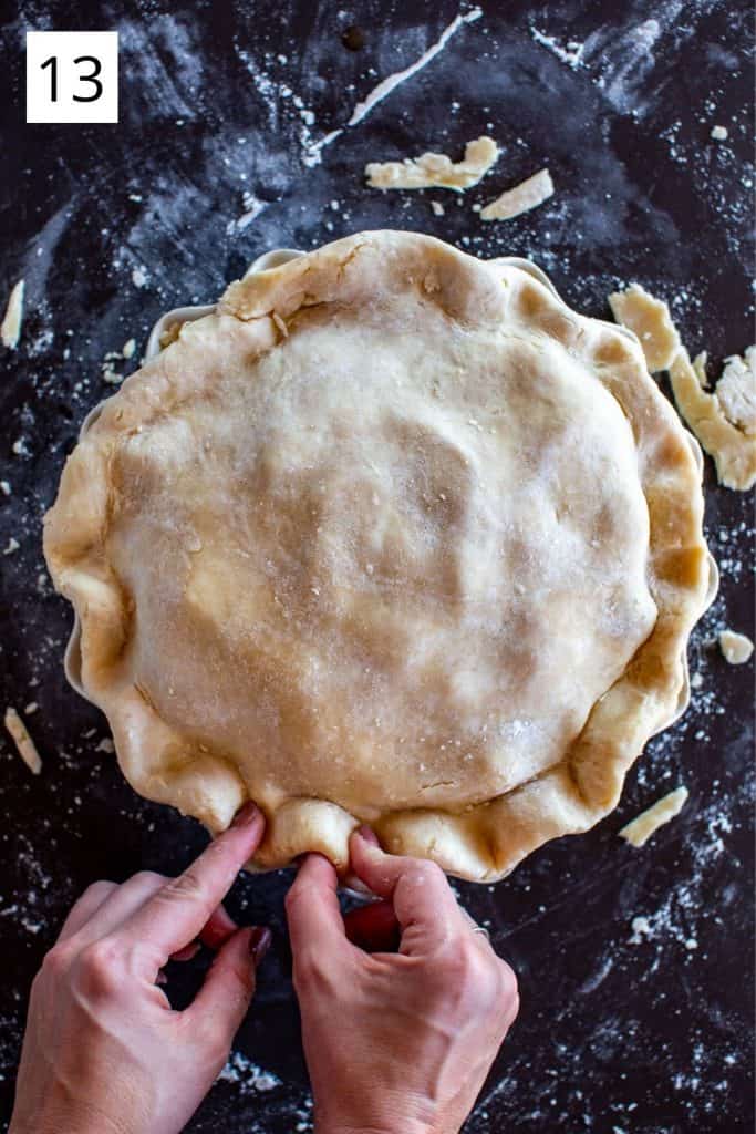 hands crimping the edge of crust on an unbaked apple pie 