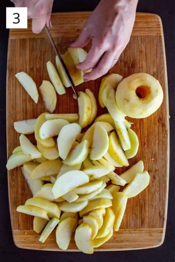 hand slicing apples on a wood cutting board