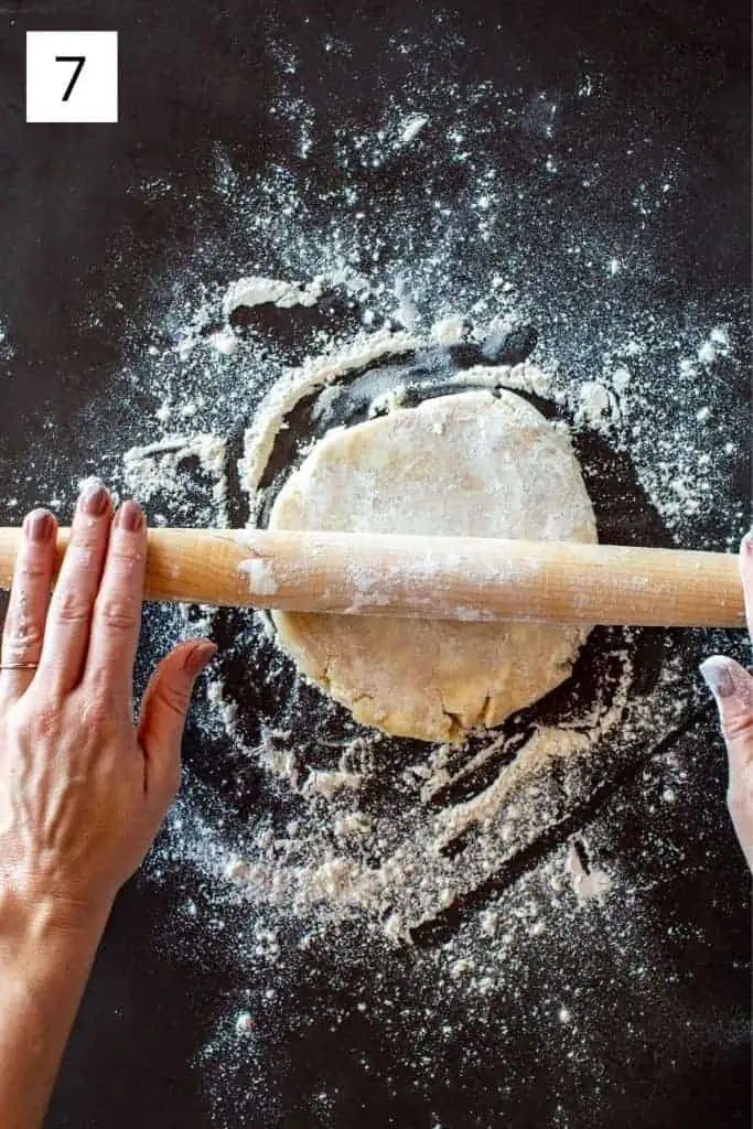 hands rolling a rolling pin over a disc of pie dough
