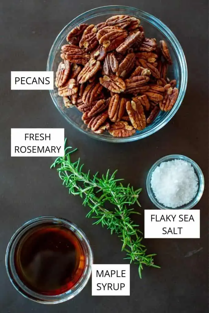 bowl of raw pecans, fresh rosemary, maple syrup and sea salt on a dark background